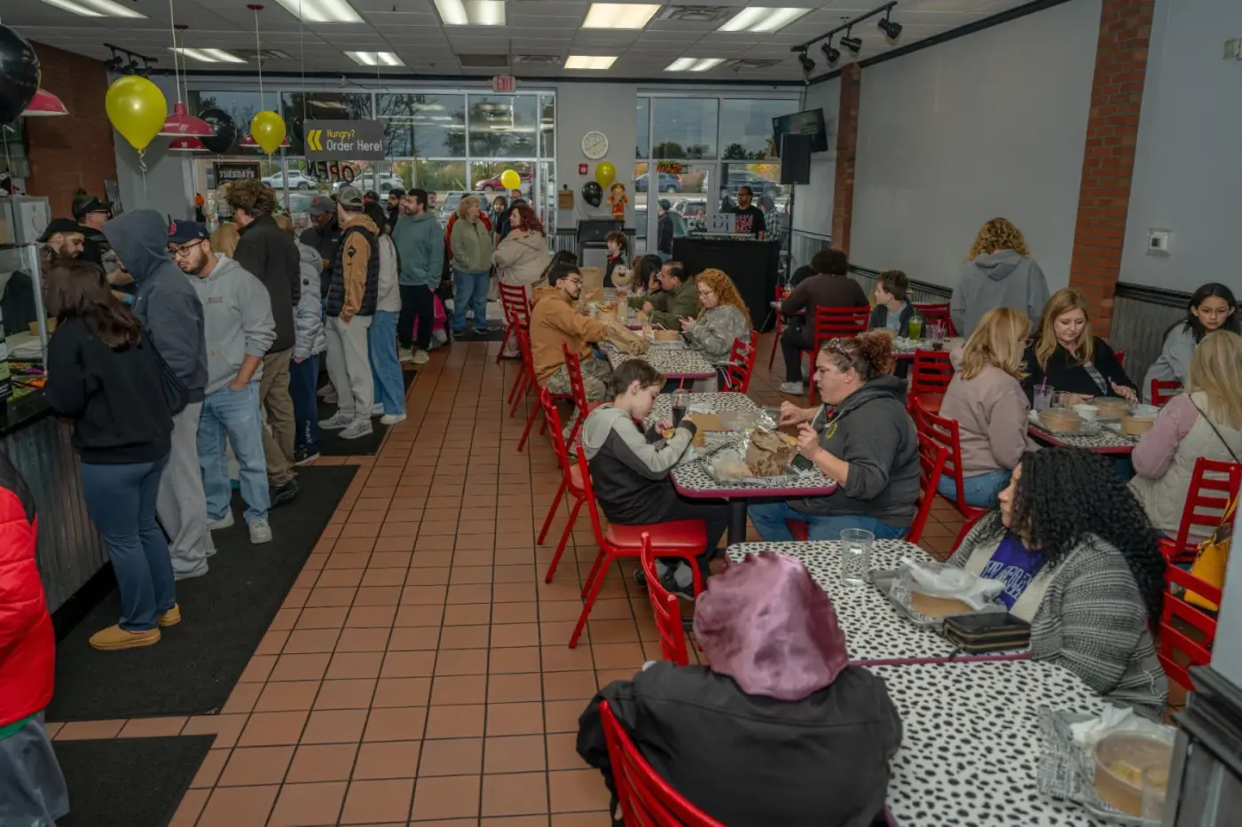 A packed AMBA dining room with a long line of guests waiting at the counter