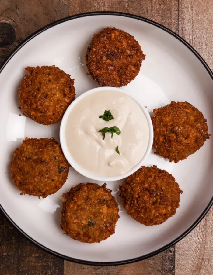 Six golden falafel around a cup of tahini sauce